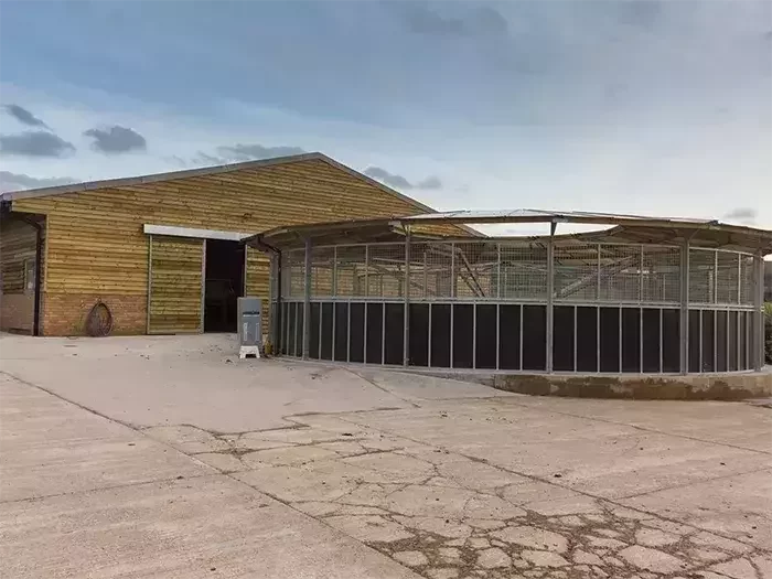 A purpose-built equestrian facility by Total Equestrian Construction, featuring a modern wooden stable block alongside a covered horse walker for safe and efficient exercise.