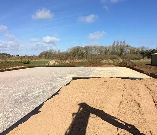 An equestrian arena under construction with a durable concrete base and precision-levelling in progress, ensuring long-lasting stability and performance.