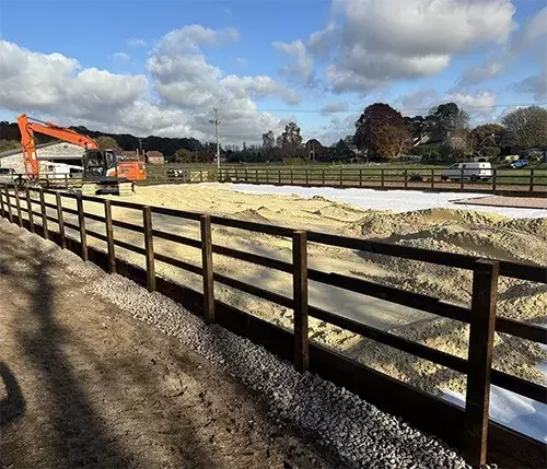 This image shows the construction of an outdoor equestrian arena with durable timber fencing, offering customisable fencing options to suit different layouts and designs.