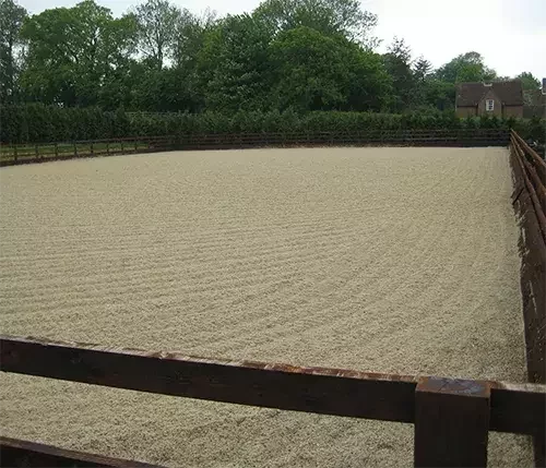 This image shows an outdoor equestrian arena with a level sand and fibre surface, designed to prevent ponding and ensure all-weather use.